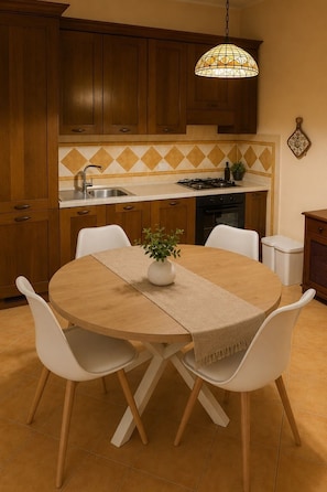 Una cocina con armarios de madera, una estufa a gas, un fregadero y una mesa de comedor con sillas.