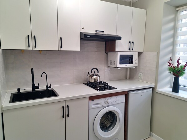 Cocina compacta con lavadora, microondas y estufa a gas.