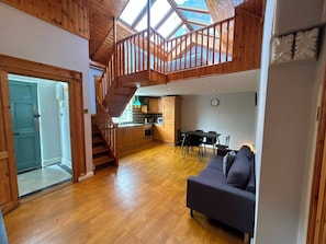 A spacious living area with a wooden staircase, a kitchen, and a dining area. - Characterful 1BDR Cottage with Loft in Dublin (Dublin)