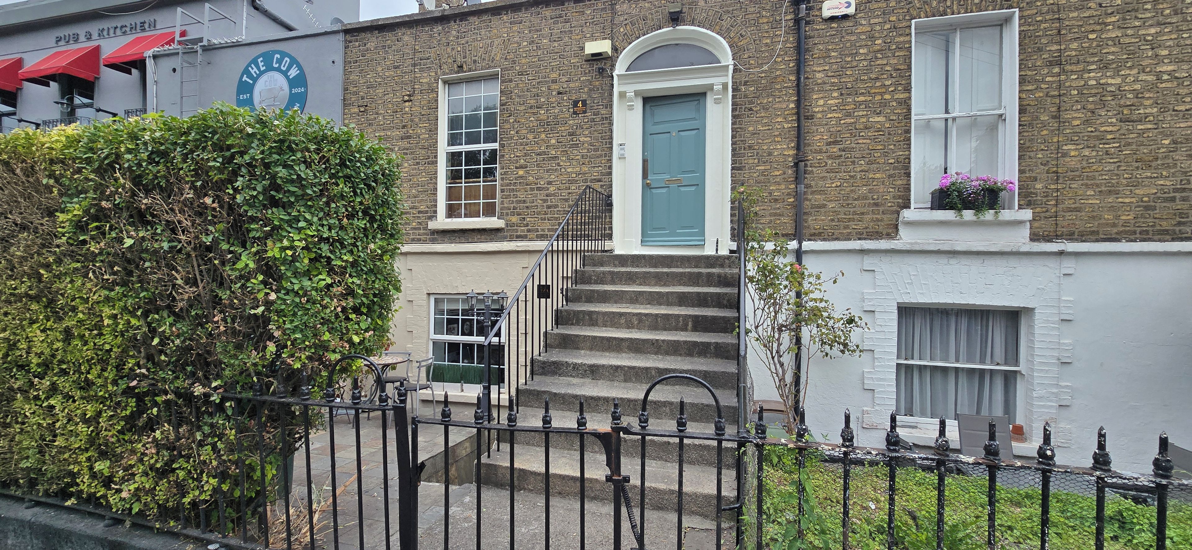 A two-story building with a blue door and a staircase leading to the entrance.