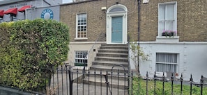 A two-story building with a blue door and a staircase leading to the entrance. - Characterful 1BDR Cottage with Loft in Dublin (Dublin)