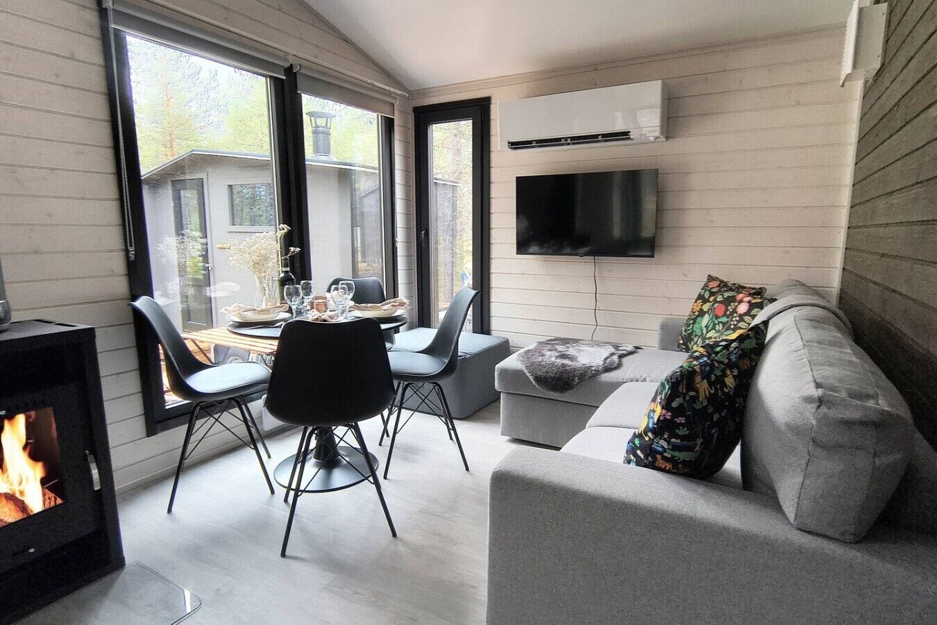 Una sala de estar moderna con chimenea, un comedor y un sofá con un plaid colorido.