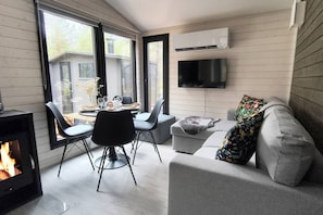 A modern living room with a fireplace, a dining area, and a sofa with a colorful throw.