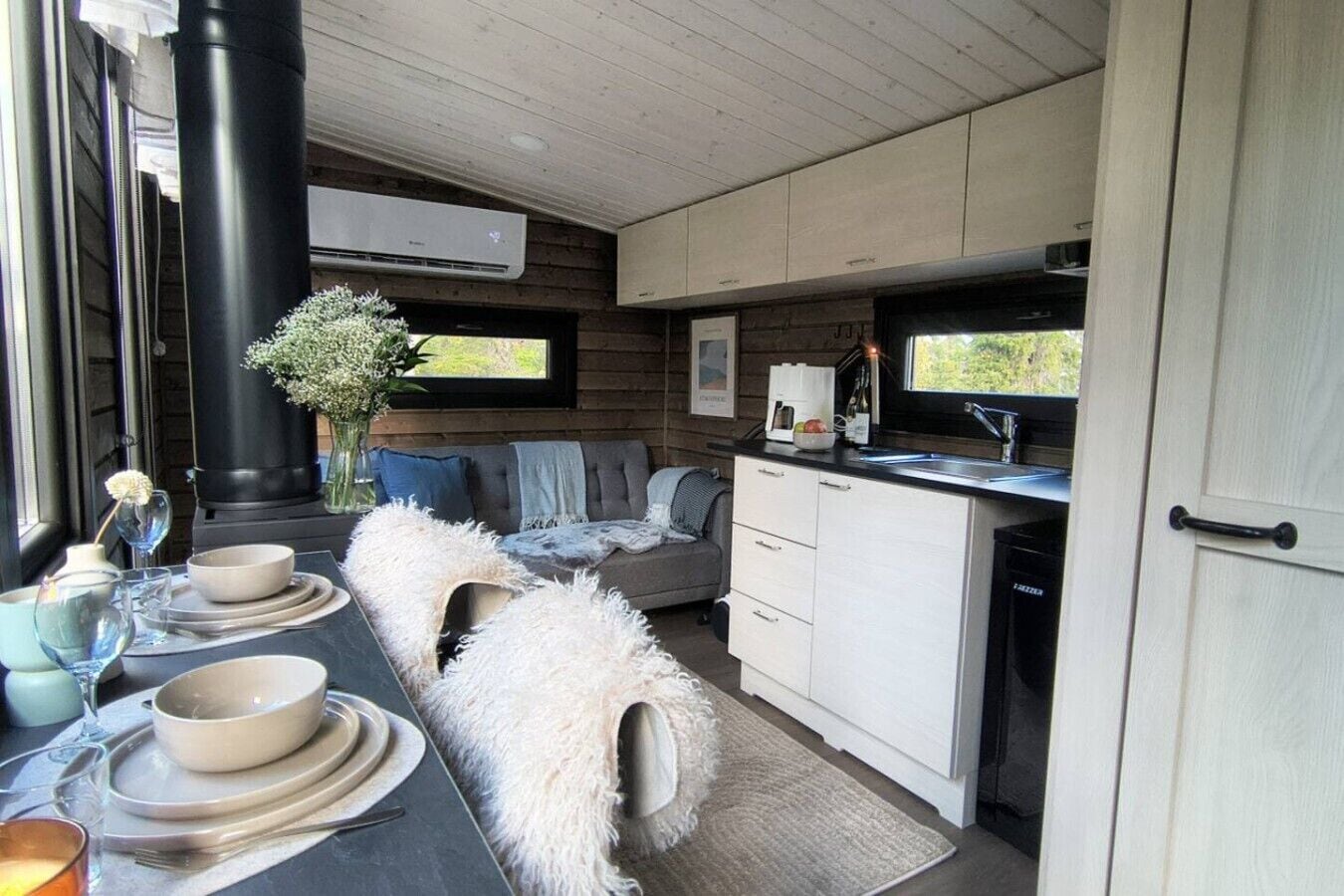 A compact kitchen with a dining area, a black stove, and a white sofa.