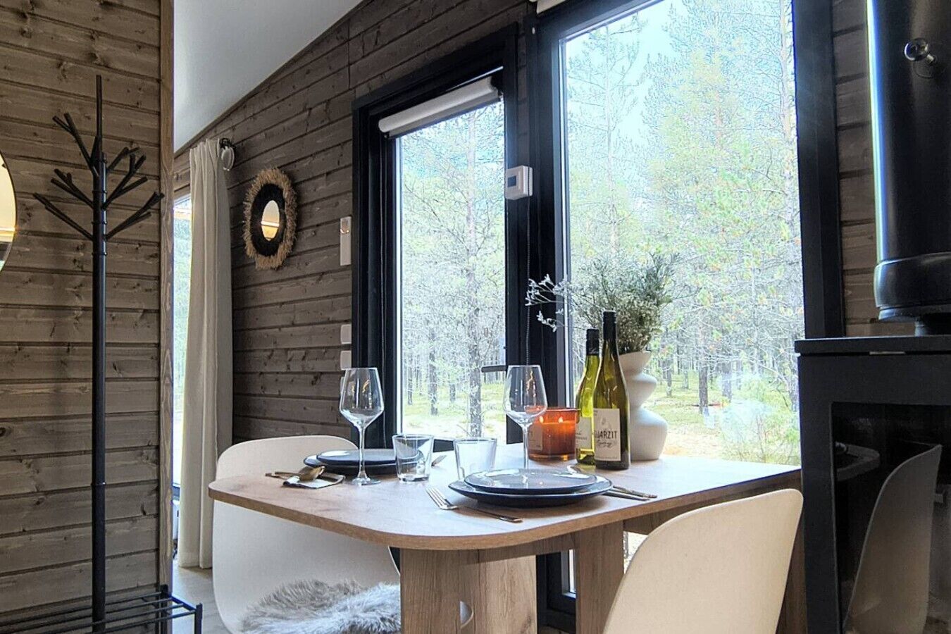 A dining area with a wooden table, two wine glasses, a candle, and a bottle of wine.