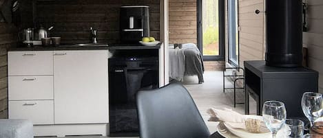 A modern kitchen with white cabinets, a coffee machine, and a black stove.