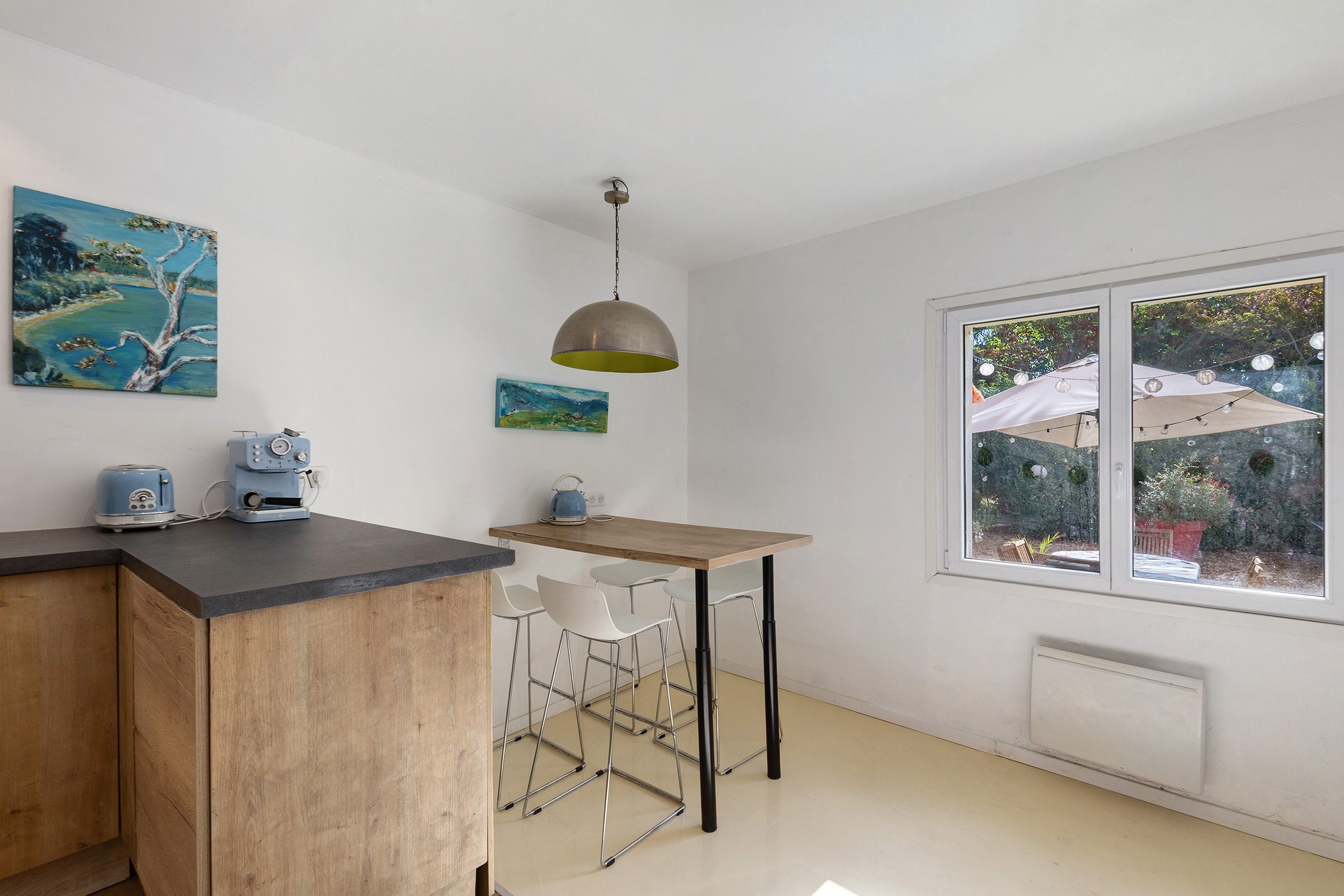 Una cocina con mostrador de madera, un hervidor y una lámpara colgante.