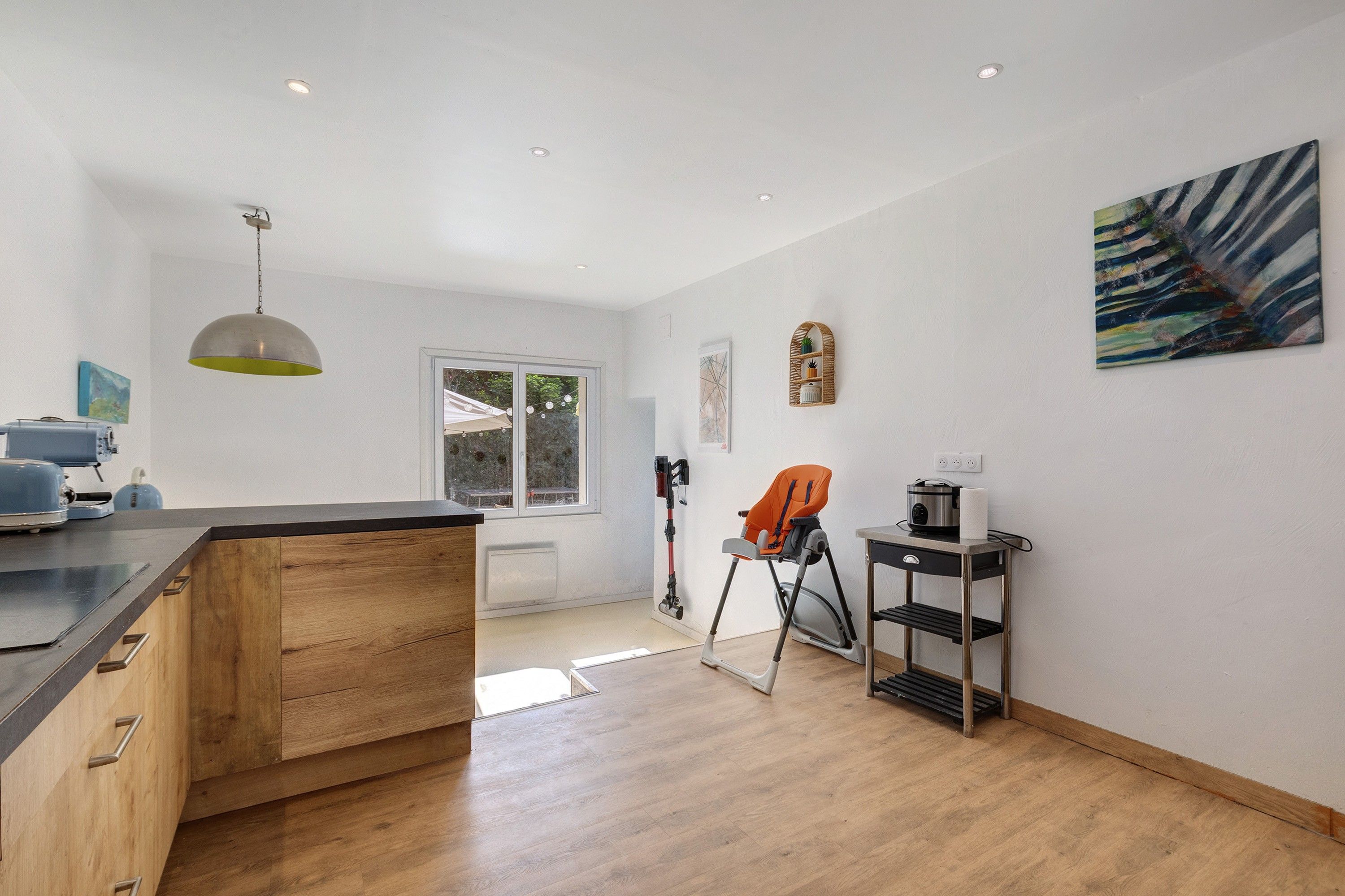 Une cuisine moderne avec des meubles en bois, un four encastré et un coin repas équipé d’une chaise haute.