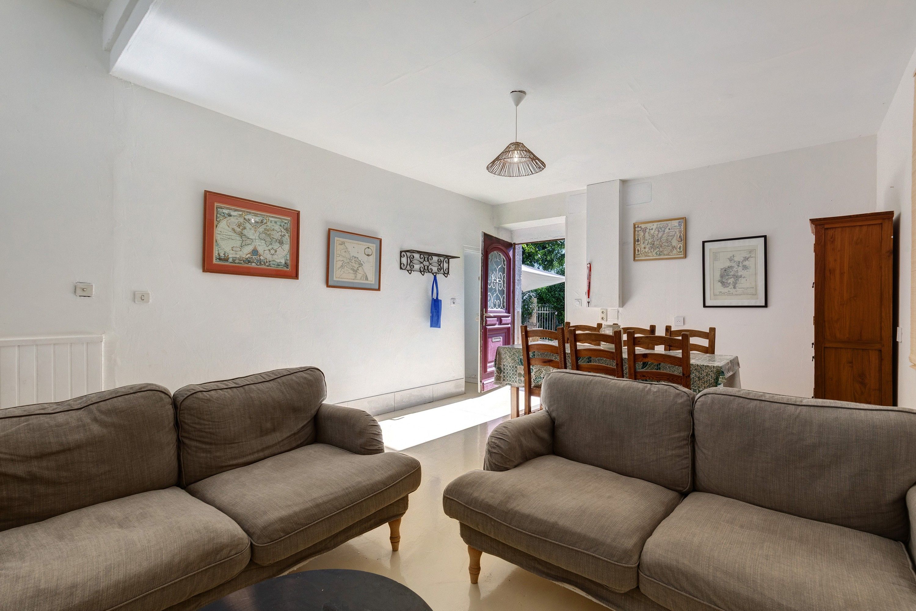 A living room with two sofas, a dining table with chairs, and a ceiling light fixture.