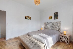 Un dormitorio con cama, una banca, una mesita de noche y decoración en la pared.