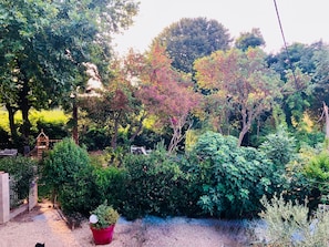 Un jardín con una estructura de juego de madera, follaje denso y un camino de grava.