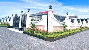 A gated entrance with a white building, black gates, and a red roof.