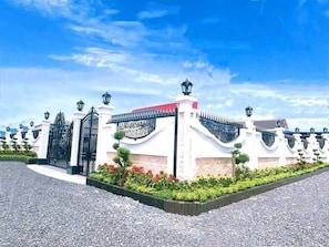 A gated entrance with a white building, black gates, and a red roof.