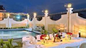 An outdoor dining area with a pool and a white fence.