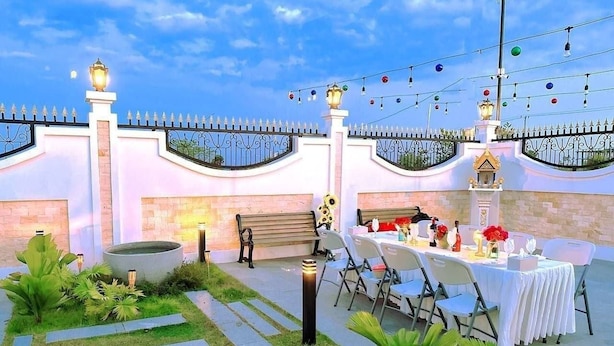 An outdoor dining area with a table set for a meal, surrounded by chairs and a decorative fence.