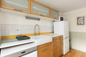 A kitchen with white cabinets, a microwave, a refrigerator, and a dishwasher. - New! Cosy 1BR Flat w/Patio in New Cross (Greater London)