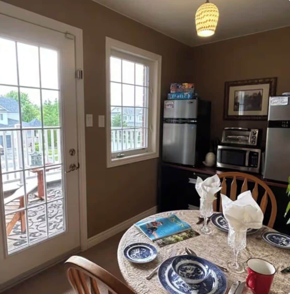A kitchen with a dining table set for two, a refrigerator, a microwave, and a toaster.