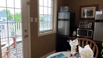 A kitchen with a dining table set for two, a refrigerator, a microwave, and a toaster.