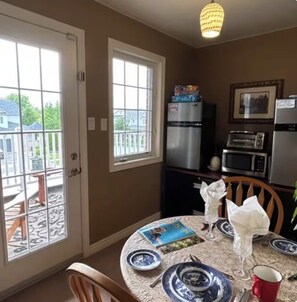 A kitchen with a dining table set for two, a refrigerator, a microwave, and a toaster.