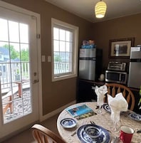 Una cocina con una mesa de comedor lista para dos personas, un refrigerador, un microondas y un tostador.