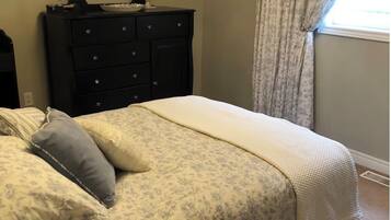 A bedroom with a bed, a dresser with a mirror, and a window with curtains.