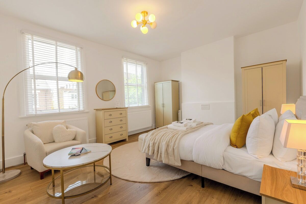 A bedroom with a bed, a dresser, a mirror, a lamp, and a round coffee table.