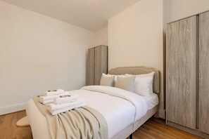 Ein Schlafzimmer mit Bett, Kleiderschrank und Nachttisch mit Handtüchern.