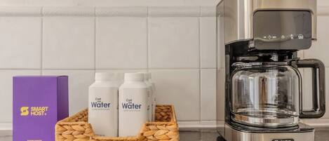 Une cuisine équipée d’une machine à café, de deux bouteilles d’eau et d’une boîte violette portant l’inscription « SMART HOST ».