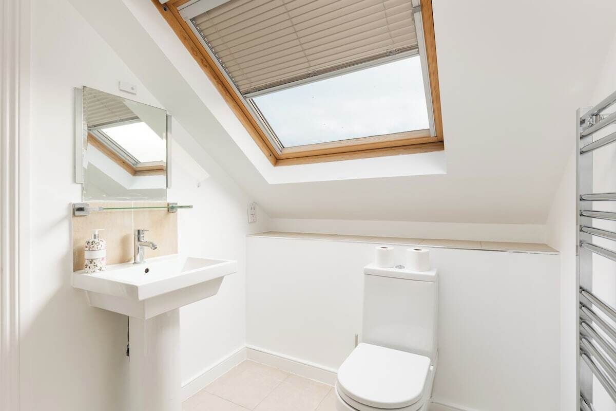 Une petite salle de bain moderne avec un puits de lumière, un lavabo blanc et des toilettes.