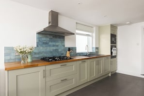 Une cuisine moderne dotée d’un îlot central, d’appareils électroménagers intégrés et d’un dosseret de carrelage bleu.