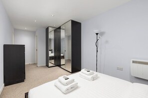 Une chambre d’hôtel équipée d’un lit, d’une armoire, d’un miroir, d’une lampe et d’un climatiseur fixé au mur.