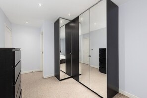 Ein Schlafzimmer mit großem Kleiderschrank, einem Bett und einem Schminktisch.