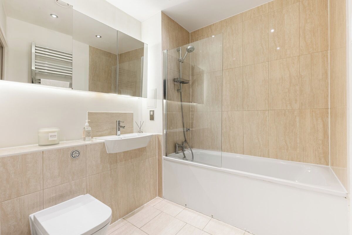 A modern bathroom with a bathtub, a glass-enclosed shower, and a toilet.