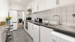 A modern kitchen with white cabinetry, a stainless steel sink, and a built-in dishwasher. - New! Charming 2BR Flat in Chelsea (Greater London)