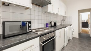 A modern kitchen with white cabinets, a built-in microwave, a stove, and a dishwasher. - New! Charming 2BR Flat in Chelsea (Greater London)