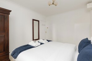 Een hotelkamer met een groot bed, een garderobe, een spiegel en een plafondlamp.