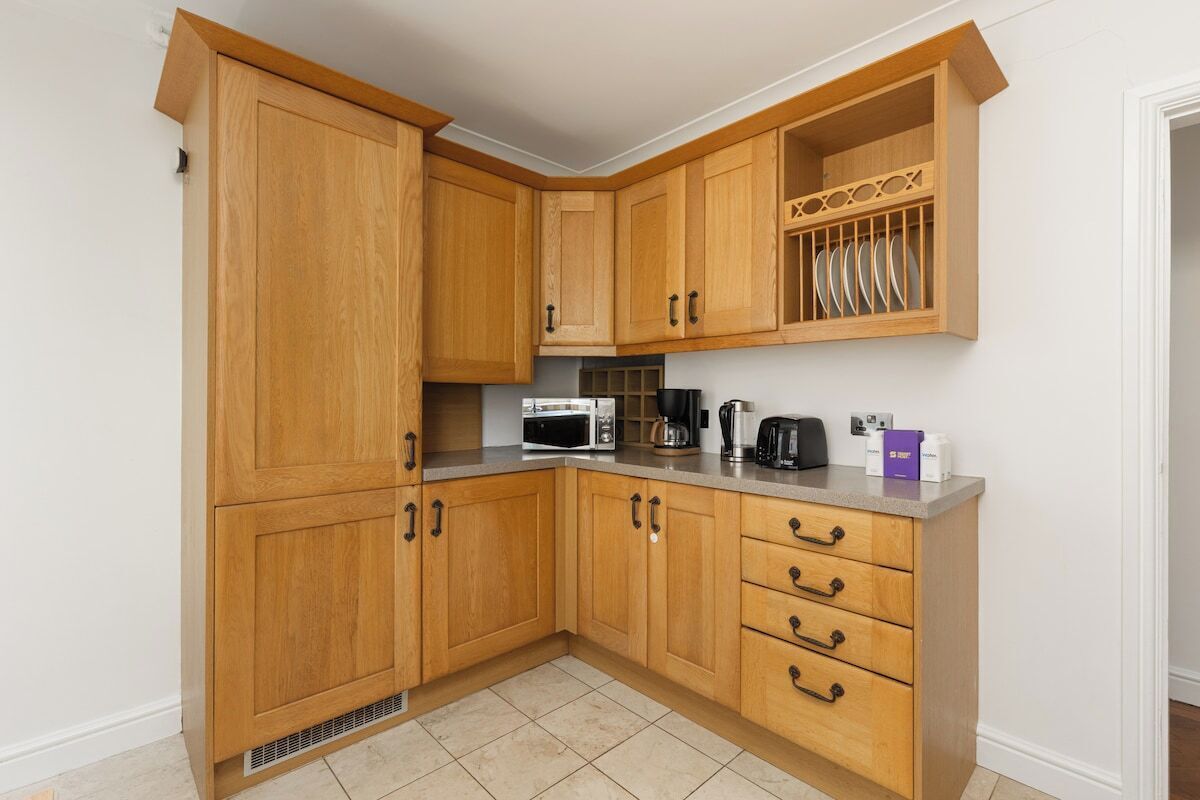 A kitchen with wooden cabinets, a microwave, a coffee maker, and a dish rack.
