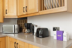 Een keuken met een magnetron, koffiezetapparaat, broodrooster en waterdispensers op het aanrecht.