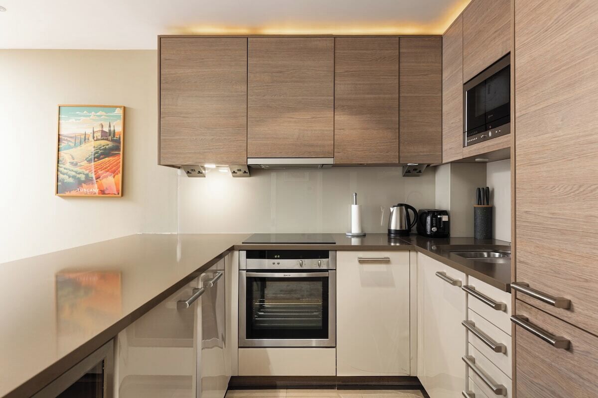 A modern kitchen with wooden cabinets, a built-in oven, and a stainless steel countertop.