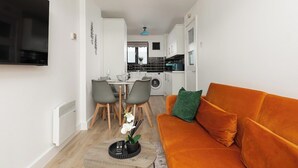 Ein kompakter Wohnbereich mit Sofa, Essplatz und Küchenzeile.