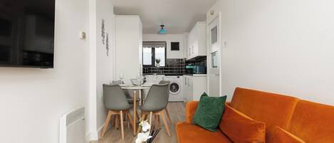 Un espacio habitable compacto con sofá, comedor y kitchenette.