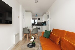 A compact living space with a sofa, dining area, and kitchenette. - New! Inviting 3BR w/ Balcony | Near Canary Wharf (Greater London)