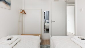 Ein Hotelzimmer mit zwei Betten, einer Holztür, einem Spiegel und einem Handtuchhalter.