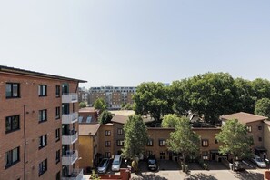 A multi-story residential building with balconies, a parking area, and trees. - New! Inviting 3BR w/ Balcony | Near Canary Wharf (Greater London)