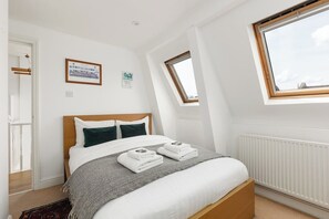 A bedroom with a bed, a window, a radiator, and a door. - New! Stylish Battersea 1BR | 6 Mins to Clapham Jct (Greater London)