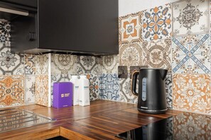 A kitchen with a black coffee maker, a purple box, and two white water bottles. - New! 2BR Flat w/Balcony & Views in Popular (Greater London)