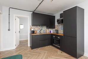 A compact kitchen with black cabinets, a wooden countertop, and a patterned backsplash. - New! 2BR Flat w/Balcony & Views in Popular (Greater London)