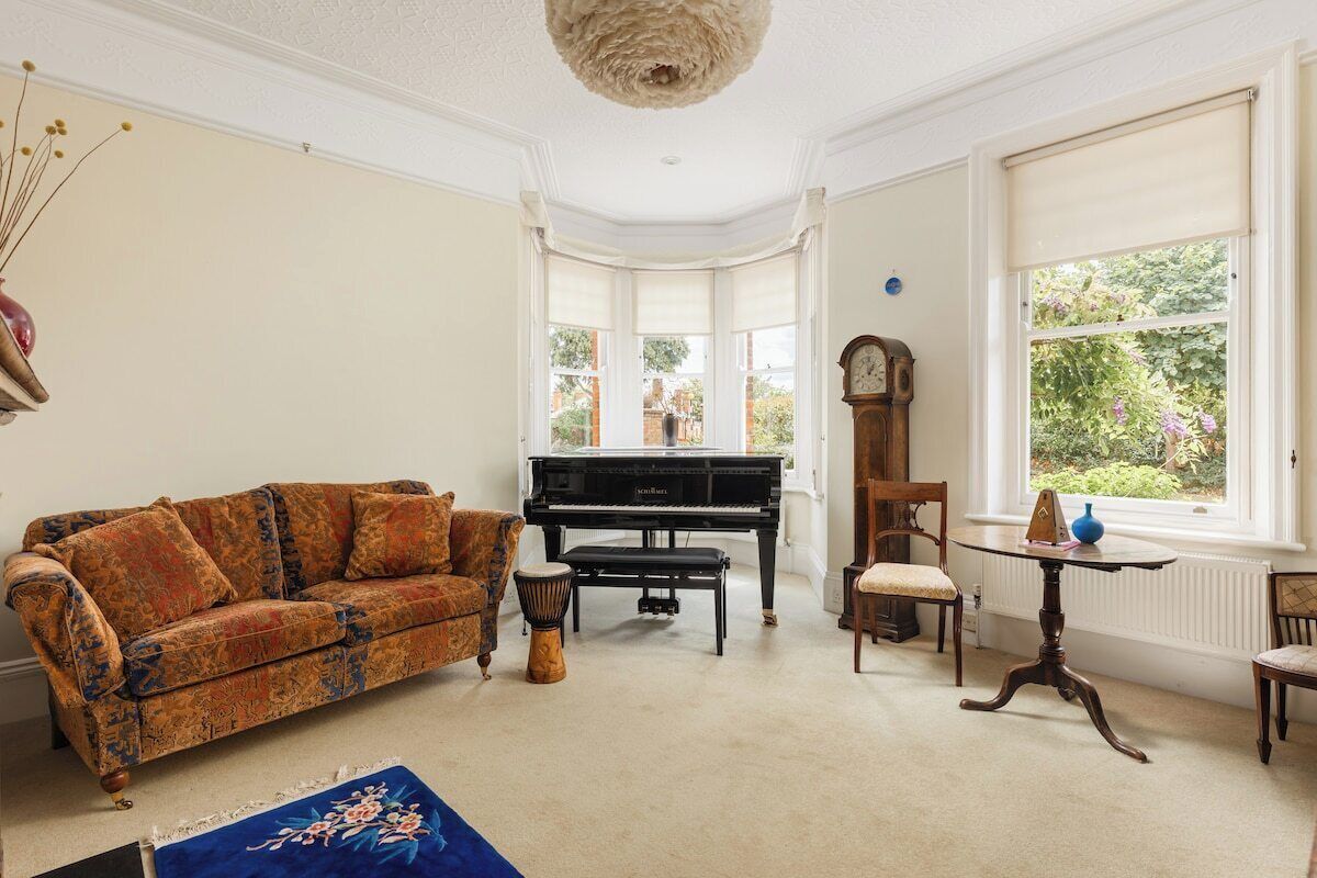 A room with a piano, a sofa, a table, and a chair.