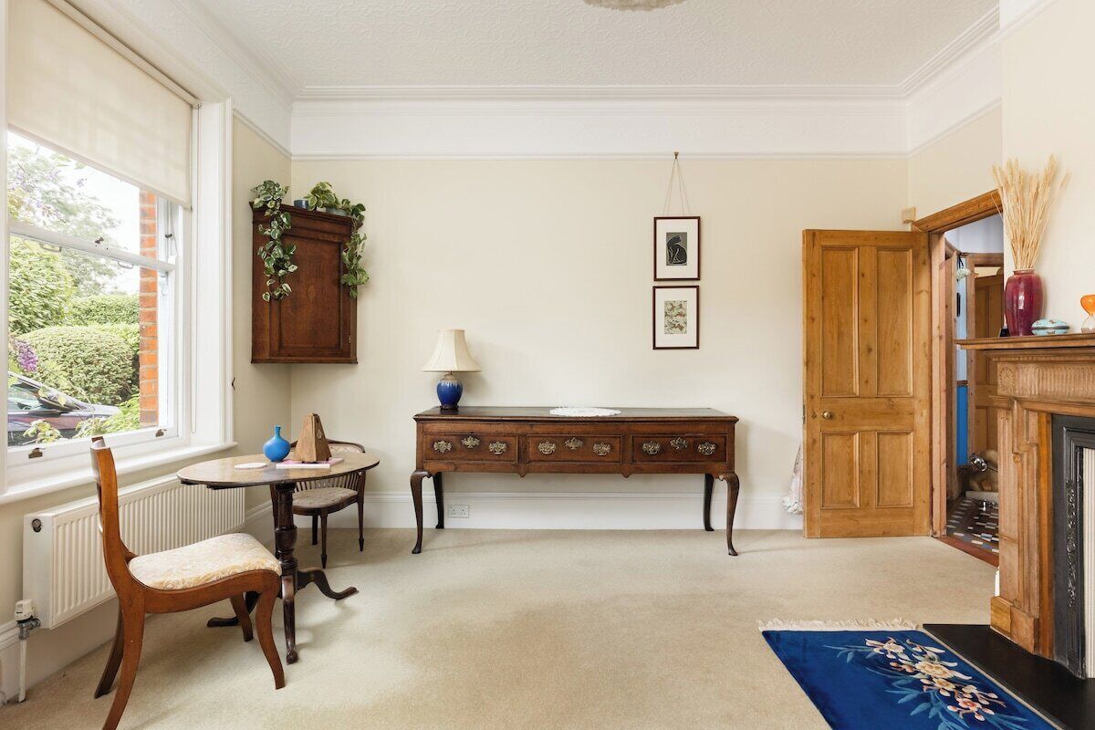 A room with a wooden cabinet, a table with chairs, a fireplace, and a door.