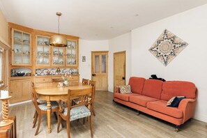 Ein Essbereich mit Holztisch und Stühlen, einem roten Sofa und einem Wanddekor.